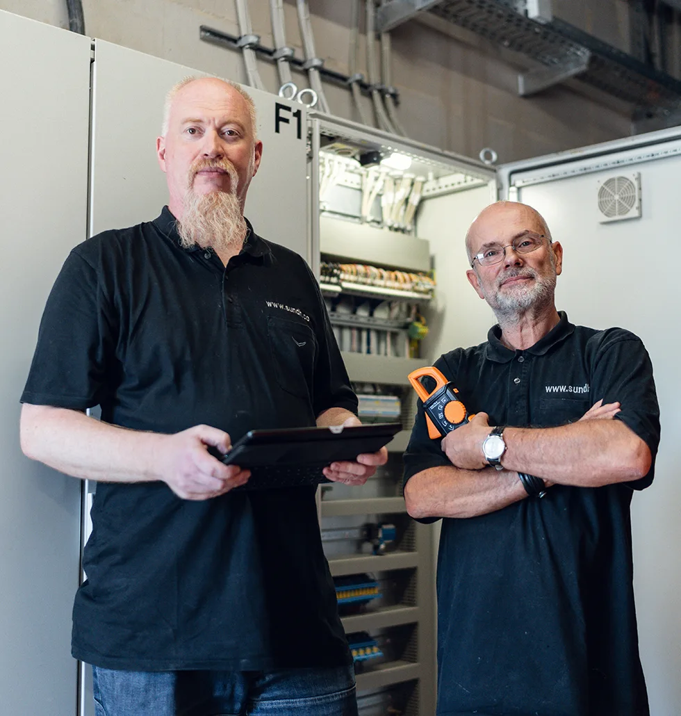 Das Team von S&H Brandschutz und Anlagenwartung vor einem geöffneten Schaltschrank